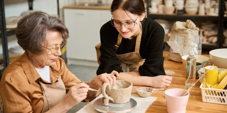 Elderly Woman Shaping Clay Pottery with an Instructor at Assisted Living Facility